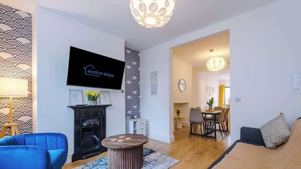 Ein modernes Wohnzimmer mit Kamin, Flachbildfernseher und Essbereich mit Stühlen und Tisch.