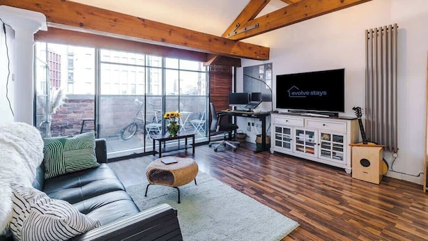 Un salon moderne comprenant un canapé, un téléviseur et un coin repas avec une table et des chaises.