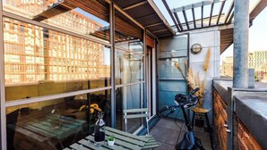 Un balcon extérieur moderne, équipé d’une table, de chaises et d’un vélo.