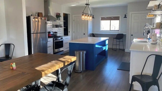 A modern kitchen with a central island, stainless steel appliances, and a dining area with a wooden table and chairs. - Charming 3-bedroom "The Rose House" in Marathon near Big Bend NP (Marathon)