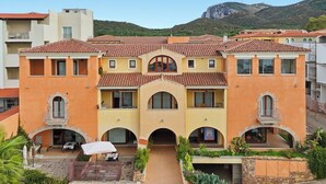 Un edificio a più piani con un cortile centrale, balconi e montagne sullo sfondo.