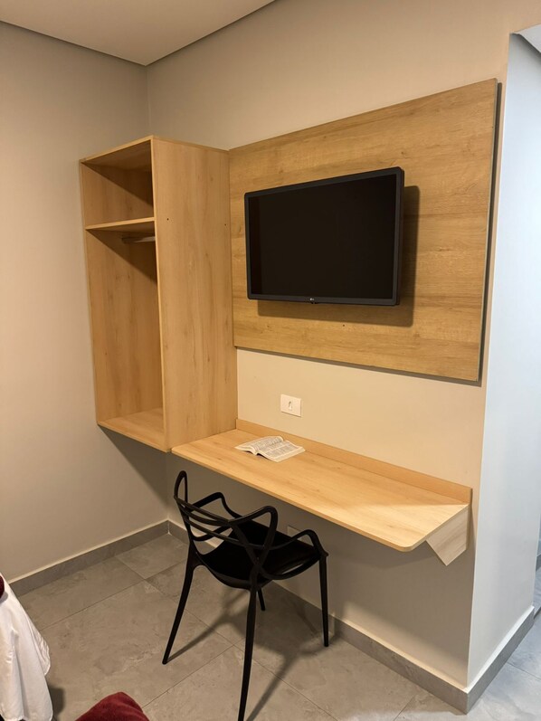A compact room with a built-in TV, a wooden desk, and a chair.