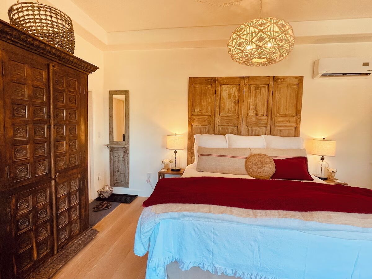 Une chambre à coucher avec un grand lit, une armoire en bois et un luminaire suspendu.