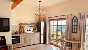 A kitchen with wooden cabinets, a sink, a chandelier, and a dining area with chairs and a table. - Ocean, Sunset, Mountain Views, Private Deck: Villa Floresco: Tuscan-like Getaway (Santa Barbara)