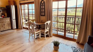 A spacious living area with a dining table, chairs, a chandelier, and large windows offering a view of the outdoors. - Ocean, Sunset, Mountain Views, Private Deck: Villa Floresco: Tuscan-like Getaway (Santa Barbara)
