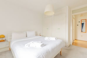Ein Hotelzimmer mit einem großen Bett, einem Nachttisch mit Lampe und einem Kleiderschrank.
