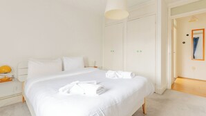 Een hotelkamer met een groot bed, een nachtkastje met een lamp en een garderobe.