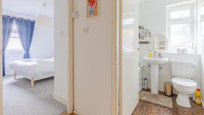 Een kamer met een bed en een badkamer met toilet, wastafel en spiegel.
