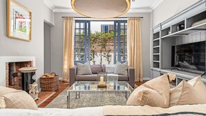 A modern living room with a fireplace, a sofa set, a coffee table, and a television. - Bellevue House - Three Bedroom House, Sleeps 6 (Cape Town)