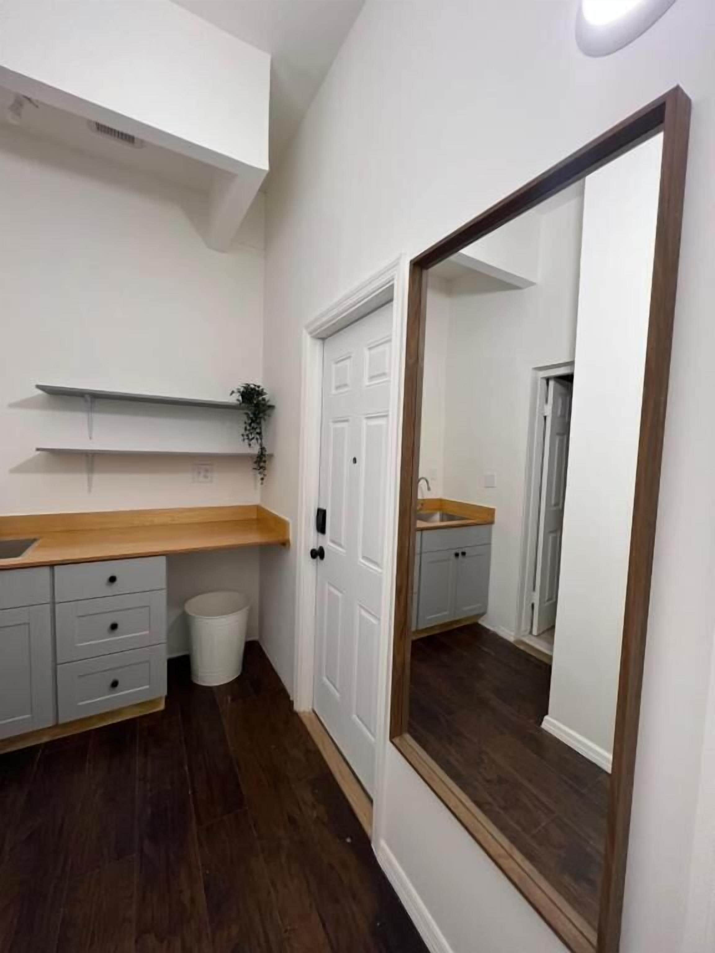 Une petite salle de bain propre, avec un meuble-lavabo en bois, un miroir et une porte blanche.