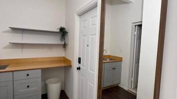 Une petite salle de bain propre, avec un meuble-lavabo en bois, un miroir et une porte blanche.