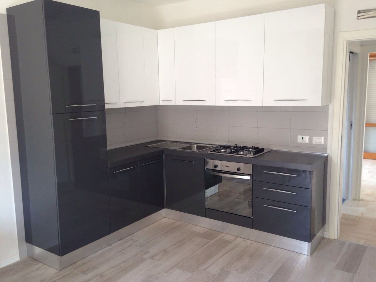 A modern kitchen with black and white cabinetry, a gas stove, and a stainless steel sink.