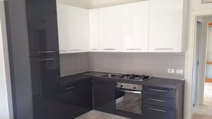 A modern kitchen with black and white cabinetry, a gas stove, and a stainless steel sink. - APARTMENT IN THE SUN OF JESOLO (Lido di Jesolo)