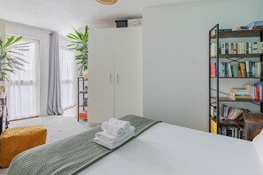 Une chambre moderne avec un lit, une bibliothèque, une plante et une fenêtre avec des rideaux.