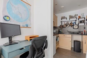 A modern kitchen with a black trash bin, wooden cabinets, and a tiled backsplash. - Bright and Trendy 1BD Canalside Flat in Hackney (Greater London)