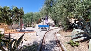 A paved pathway leading to a playground with swings and a blue bench. - Panoramic apartment with pool 2 - Liberato Puglia (Peschici)