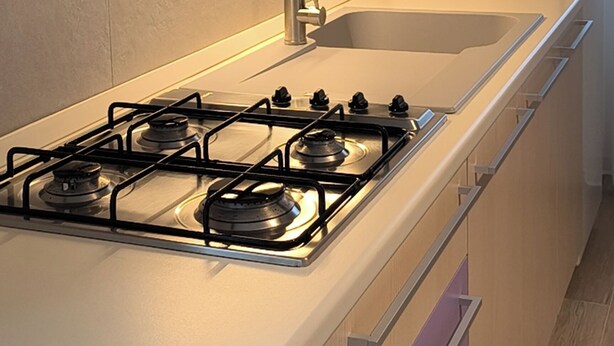 Una cocina con estufa a gas, un lavaplatos y armarios de madera.