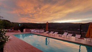 Una piscina con sillones de descanso y vistas al paisaje.