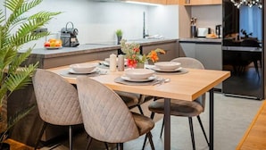 Een moderne keuken met houten kastjes, een centraal eiland en een eethoek met twee stoelen.