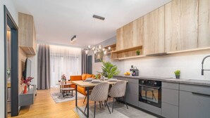 Een moderne keuken met grijze kastjes, een houten eettafel en een inbouwoven.