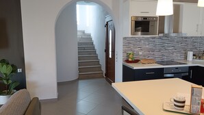Eine moderne Küche mit Einbauofen, ein Essbereich mit Tisch und Stühlen sowie eine Treppe zu einer weiteren Ebene.