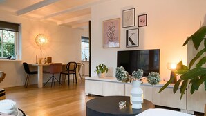 A modern living room with a dining area, a TV, and artwork on the wall.