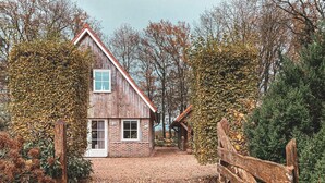 A rustic wooden house with a brick pathway leading to the entrance.