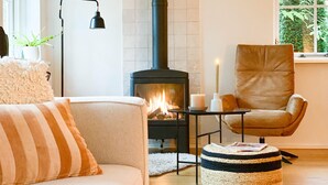 A cozy living room with a sofa, a chair, a small table with candles, and a fireplace.
