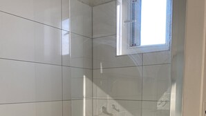 A small, tiled shower room with a window, a radiator, and a door. - 8P 5B Business Stay StPhilipsland for Expats (Sint Philipsland)
