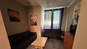 A living room with a dark brown sofa, a wooden coffee table, and a brown couch. There is a painting of a flower on the wall. - 8P 5B Business Stay StPhilipsland for Expats (Sint Philipsland)