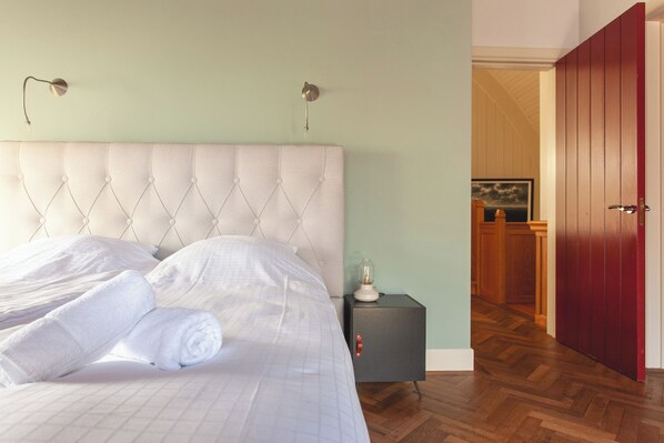 A neatly made bed with white linens and rolled towels, a bedside table with a lamp, and a wooden floor. - 10P 4B Villa with Pool and Sauna in Spijkerboor (Spijkerboor)