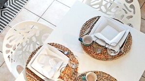 A dining area with two white tables, each set with plates, cutlery, and glasses.