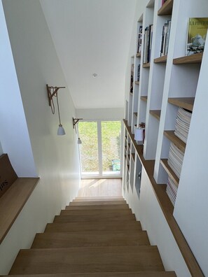 A staircase leading to a bright room with a view of greenery outside. - Portzic Beach House—within walking distance · Sheltered, south-facing garden (Crozon)
