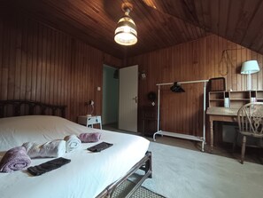 Ein Zimmer mit Holzwänden, einem Bett, einem Schreibtisch und einem Sessel.