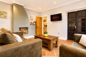 A living room with a fireplace, a wooden coffee table, and a TV mounted on the wall. - Large Groups | Contractors | Darlington | Sleeps 6 (Darlington)