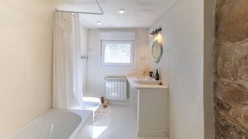 Un baño con bañera, lavabo, espejo y ventana.