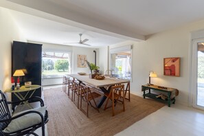 Un espace repas comprenant une longue table, des chaises, un banc et un ventilateur de plafond.