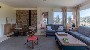 Una sala de estar acogedora con una pared de piedra, un sofá, una mesa de centro y vistas al exterior.