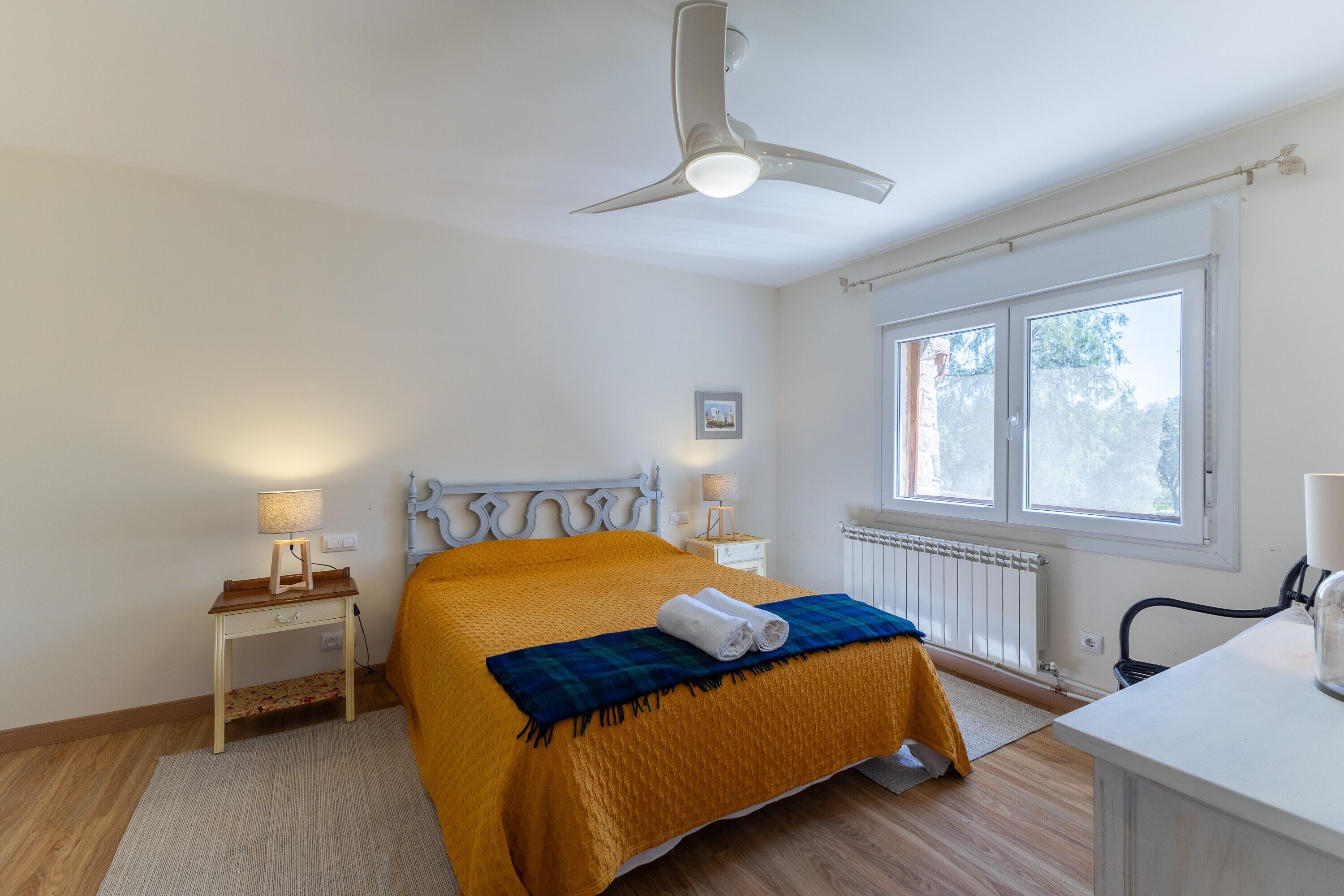 Una camera da letto con un letto, un comodino, una lampada, un termosifone e una finestra.