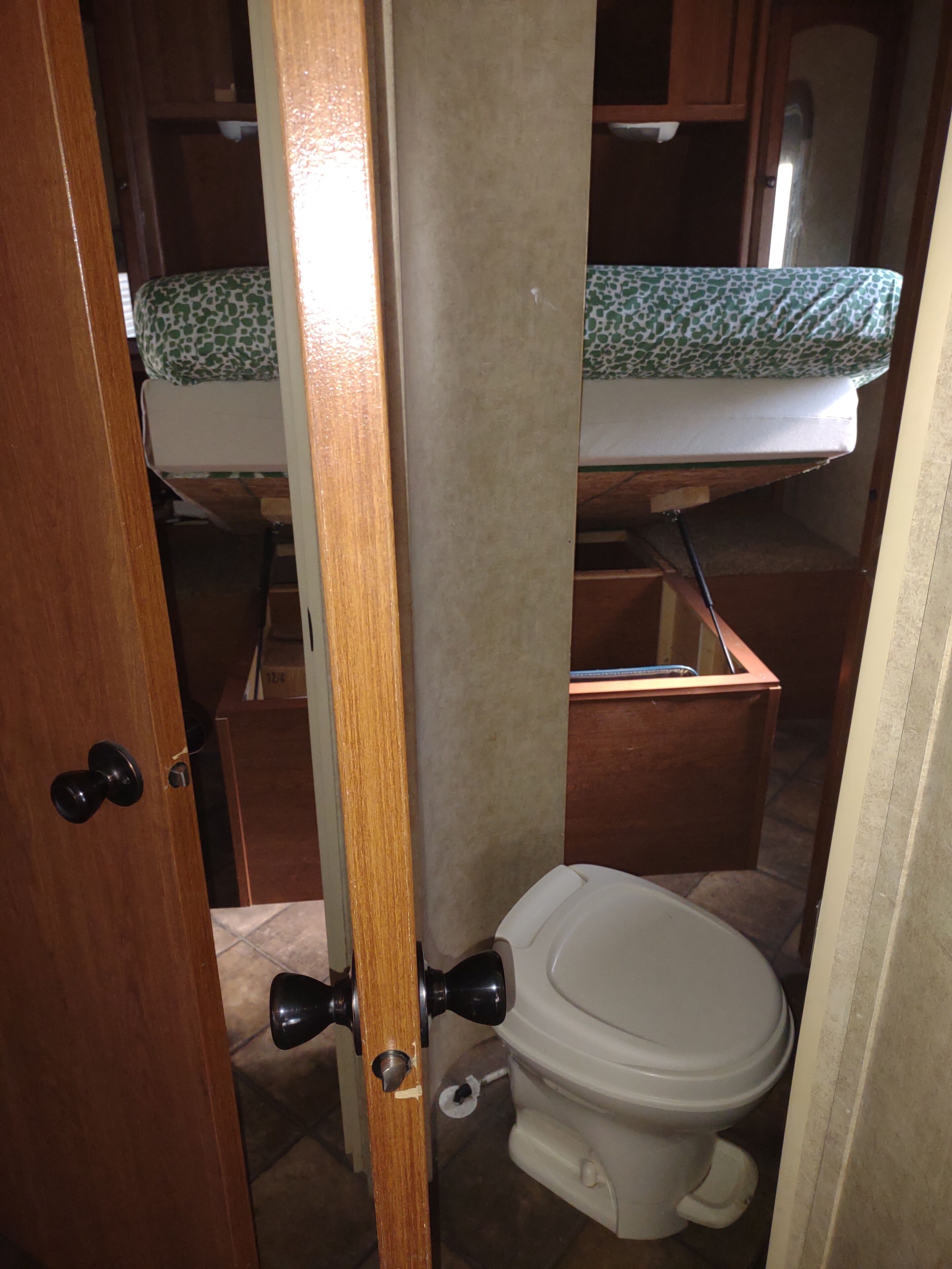 Une petite salle de bain comprenant des toilettes, un lavabo et une petite étagère au-dessus des toilettes.