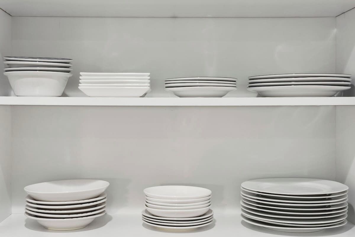 A storage unit with multiple shelves holding stacks of white plates and bowls.