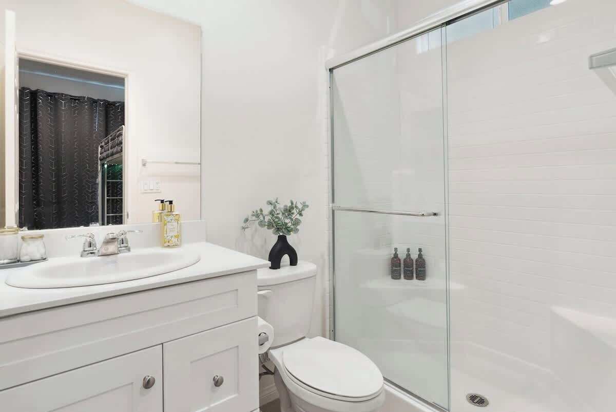 A modern bathroom with a white vanity, a glass shower enclosure, and a toilet.