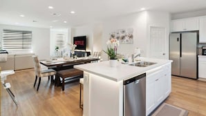 A modern kitchen with white cabinetry, a central island, and a built-in dishwasher. - Family-Friendly Retreat, 20min to Disney & OC (Santa Ana)