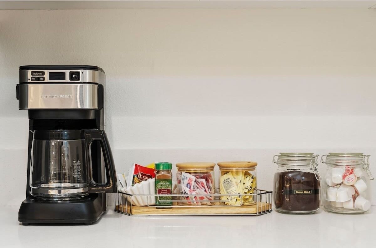 A kitchen with a coffee maker, a spice rack, and jars of ingredients.
