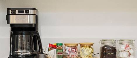 A kitchen with a coffee maker, a spice rack, and jars of ingredients.