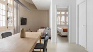 A modern hotel room with a wooden dining table, a sofa, a bed, and a TV mounted on the wall. - Tabas Cena Carioca (Rio de Janeiro)