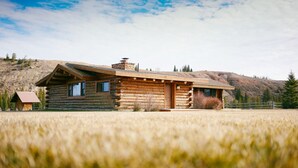 A log cabin with a sloped roof, a chimney, and a small porch. - Charming Riverside Ranch Retreat with Horse Pasture Views (Bondurant)