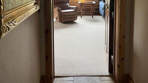 A hallway leading to a room with a large window, a leather chair, and a small table. - Private Pond-Side Manor on a Working Wyoming Ranch (Bondurant)