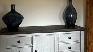 A white dresser with six drawers and two dark vases on top.