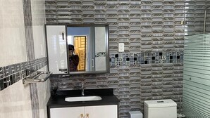 Moderni kylpyhuone, jossa on kuvioitu seinä, peilillä varustettu pesuallas ja wc-istuin.